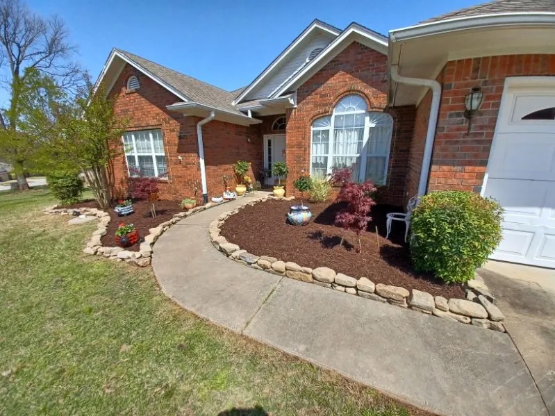 Brick home with a curved walkway and stone-edged mulch beds