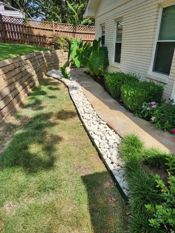 Dry creek river rock drainage bed along a home