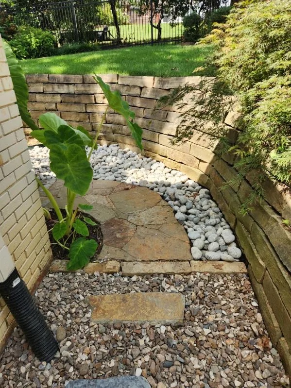 Flagstone and river rock drainage in a retaining wall corner