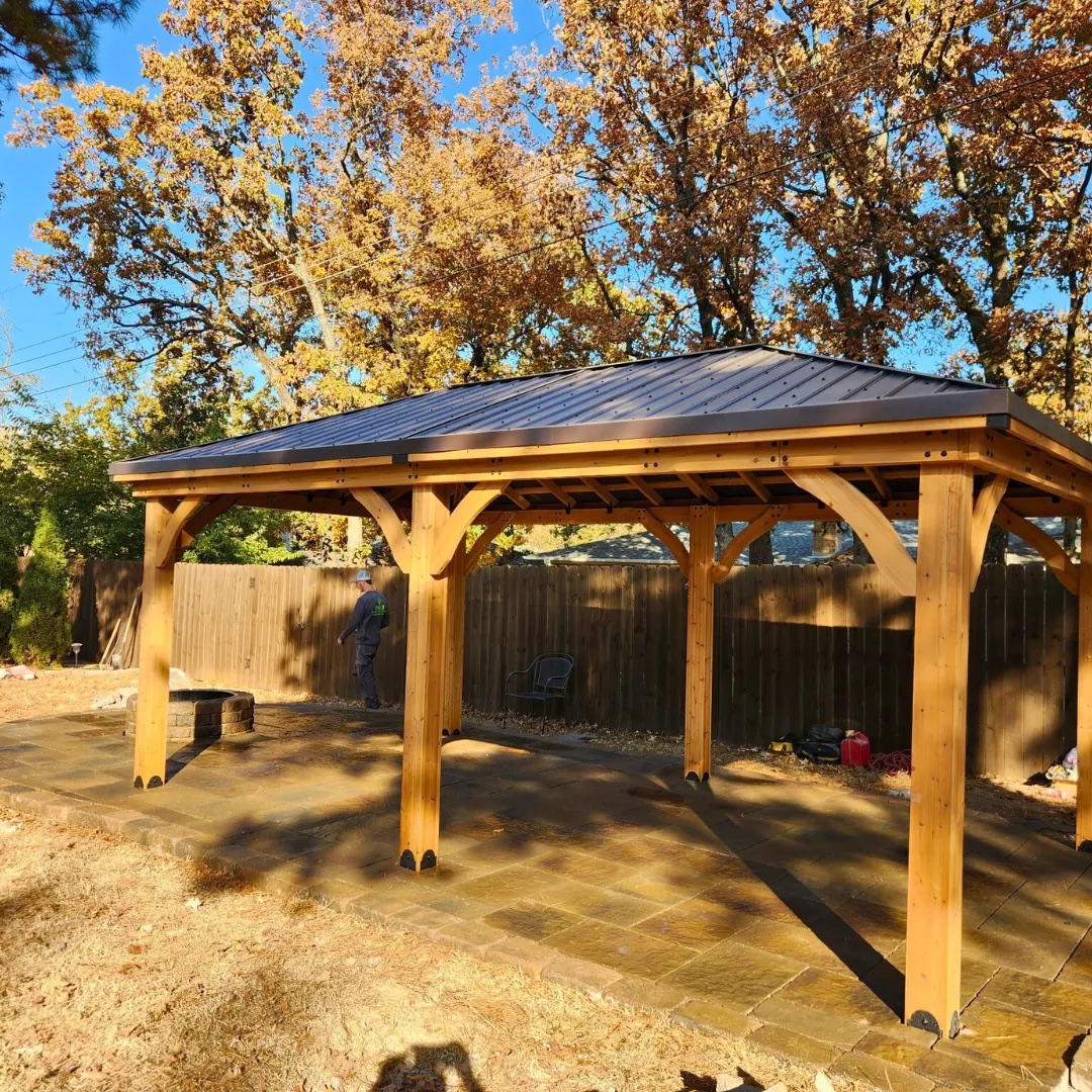 Paver patio and stone fire pit under a pavilion in autumn
