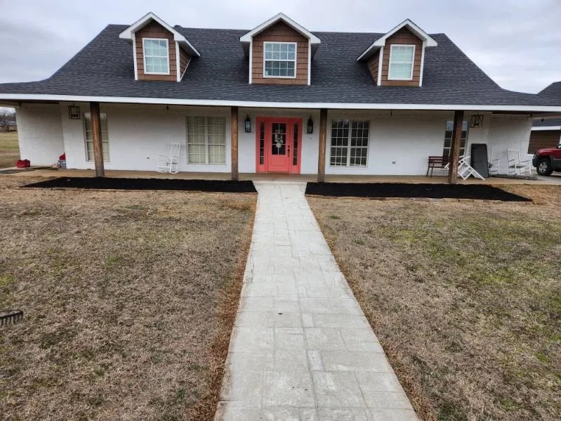 White brick home with a new paver walkway and mulch beds